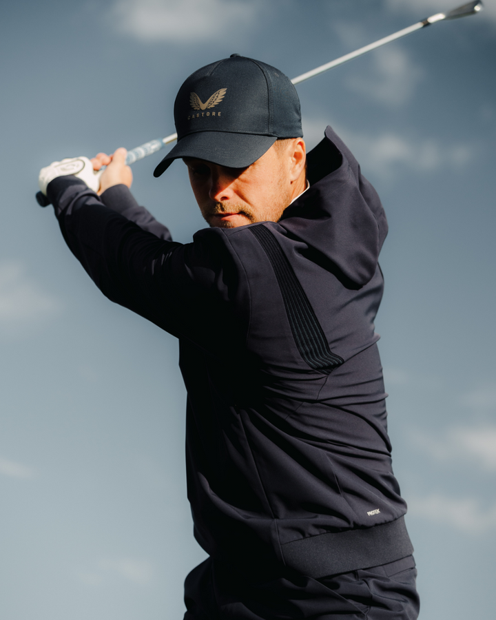 Golfer wearing midnight navy Pinnacle Performance Hoodie swinging a golf club.