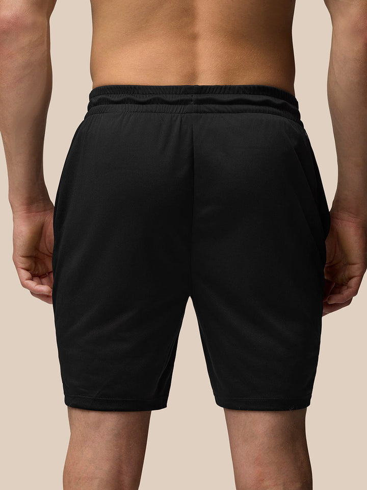 Back view of male model wearing black Adapt Training 7 inch shorts with an elastic waistband.