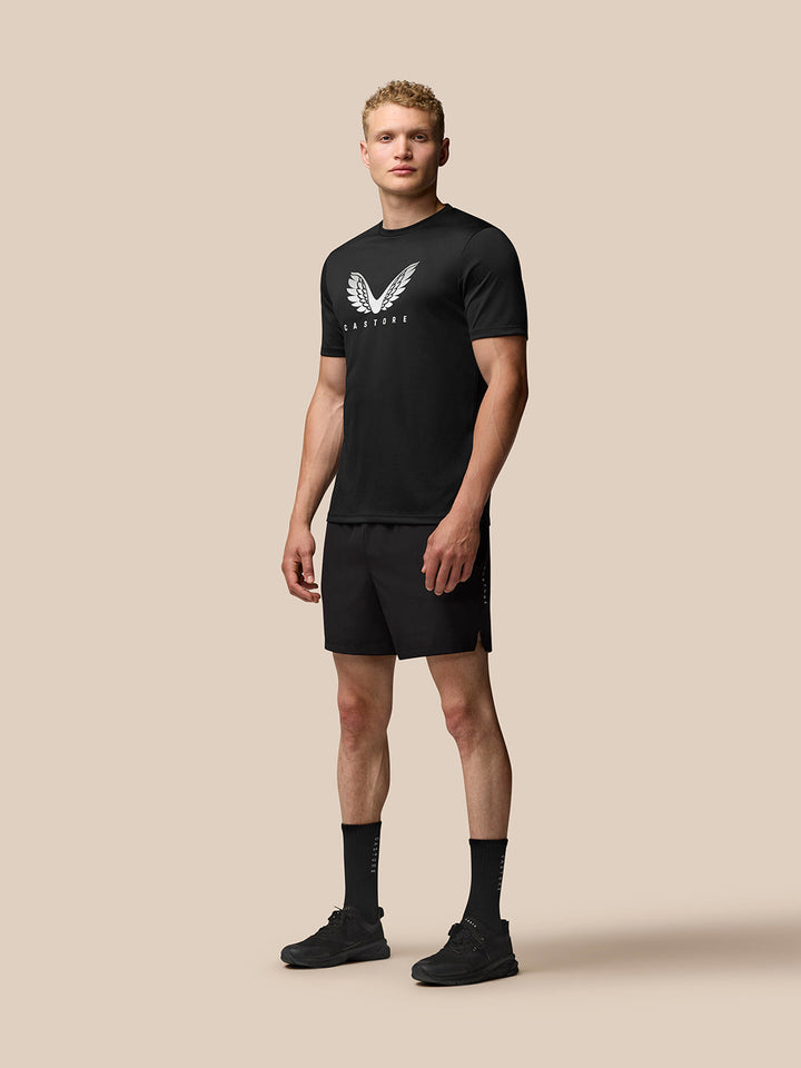 Full body shot of a man in black Adapt Training T Shirt with Castore wings logo, black shorts and athletic footwear