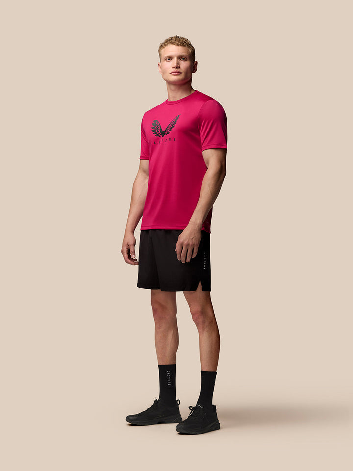 Male model wearing pink Adapt Short Sleeve Graphic T Shirt with large wings logo on chest and black shorts