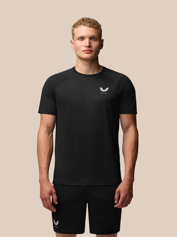 Male model wearing black Adapt Training T Shirt and matching shorts against a beige backdrop