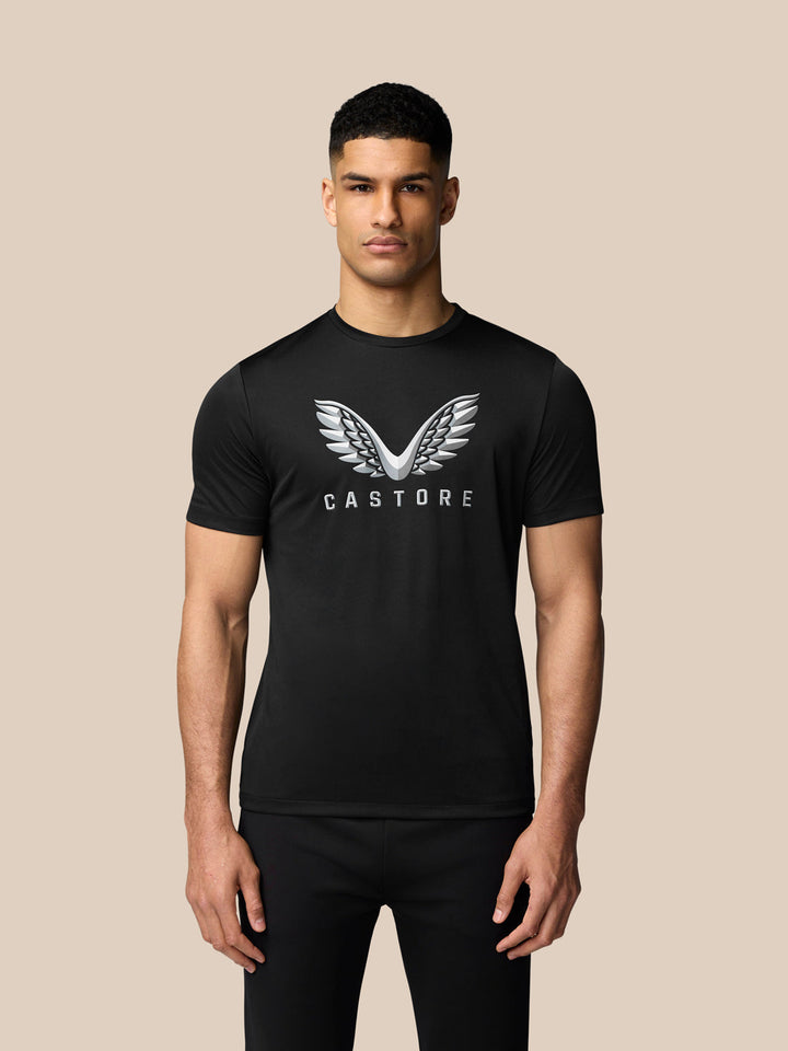 Male model in a black Graphic Training T-Shirt featuring a large silver wing logo and Castore branding