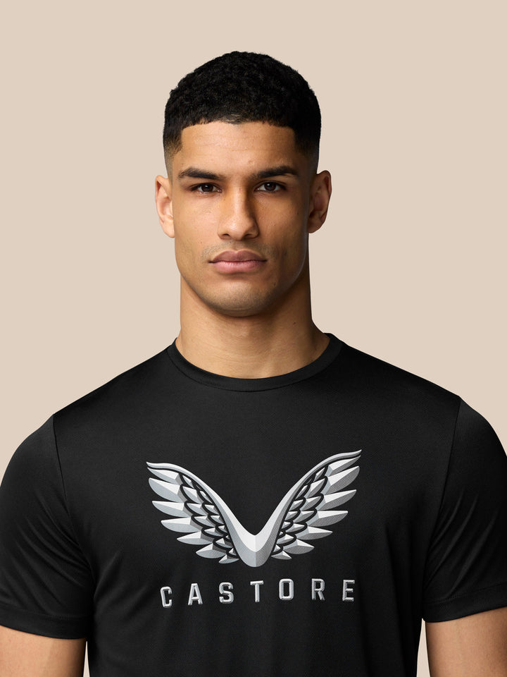 Close up of male model in black T shirt showcasing Castore wings graphic on chest