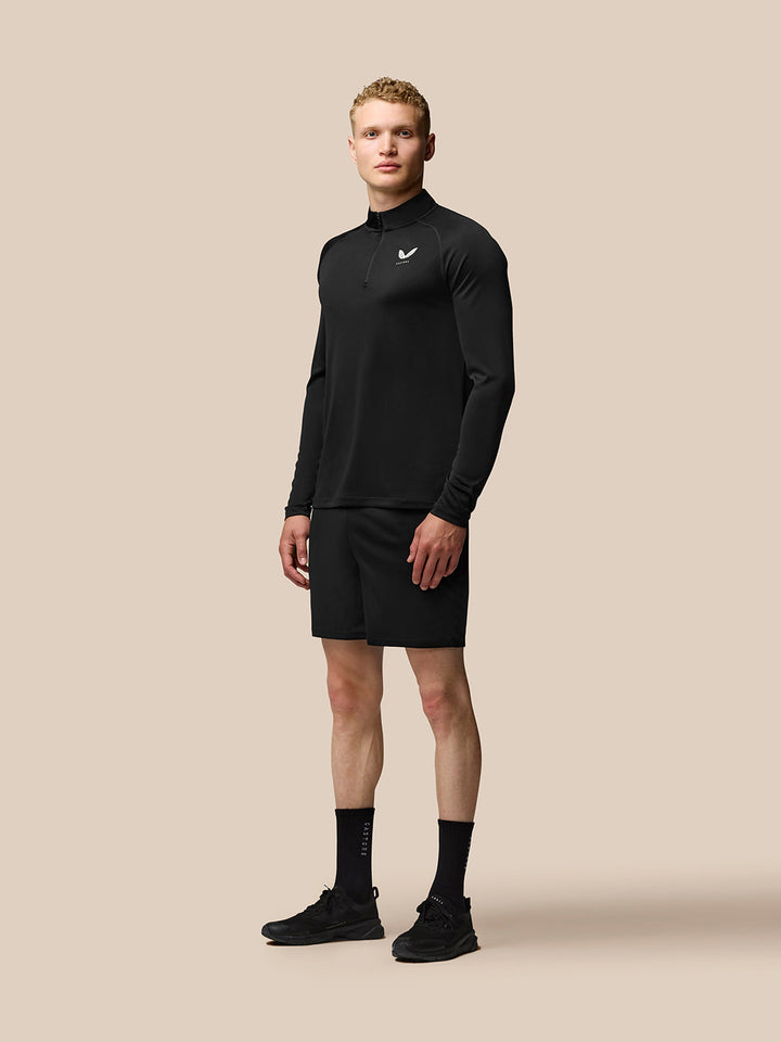 Full body shot of a man in a black Adapt Training long sleeve quarter-zip top with a stand collar and athletic fit.