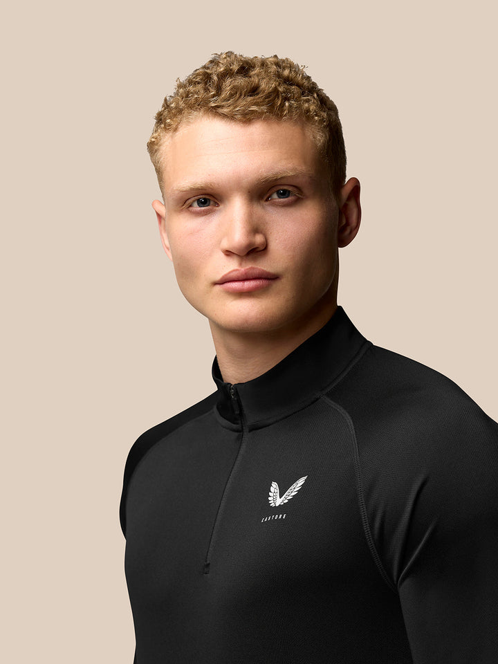 Model wearing black Adapt Training long sleeve quarter-zip top with stand collar and Castore branding on the left chest.