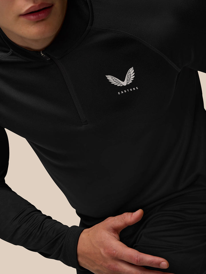 Close-up of black Adapt Training quarter-zip top with a white Castore logo on the chest and a standing collar.