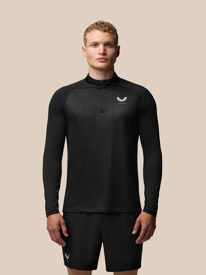 Model wearing black Adapt Print Quarter Zip Top with geometric pattern and stand collar, Castore logo on left chest.