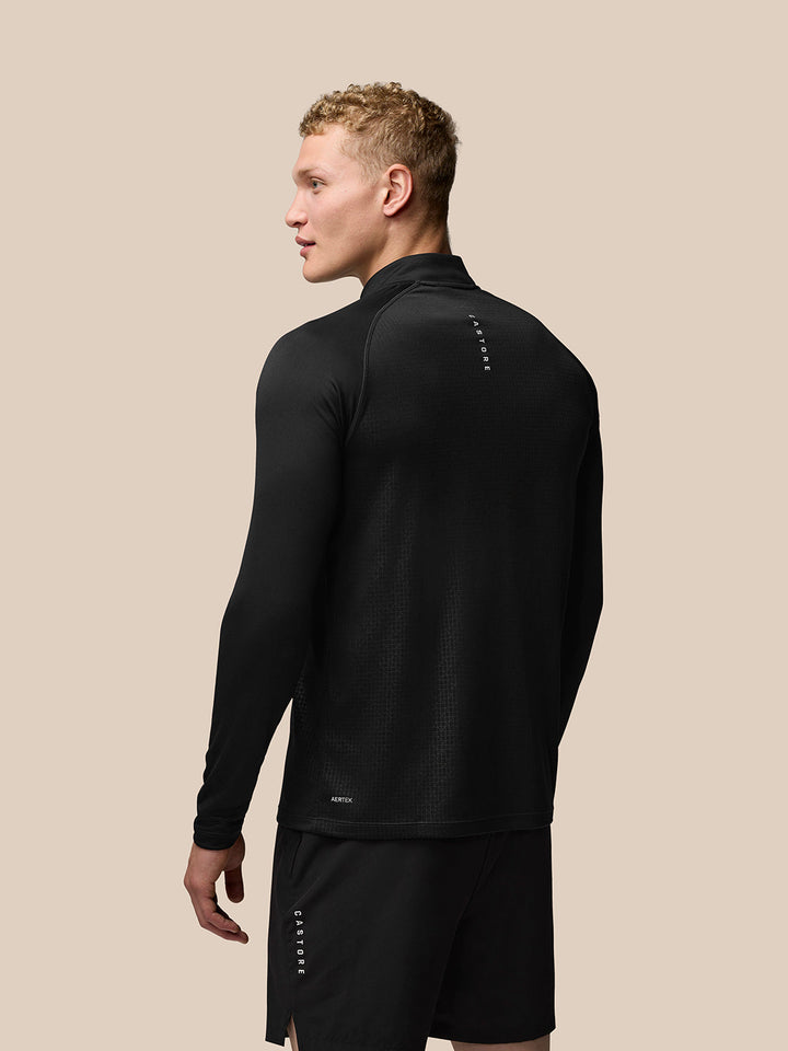 Back view of model in black Adapt Print Quarter Zip Top with Castore branding on upper back.