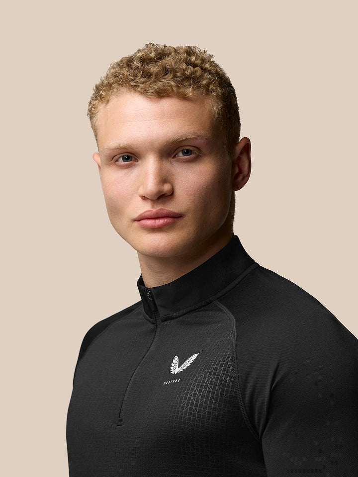 Back three-quarter view of black Adapt Print Quarter Zip Top with Aertek branding at lower back and subtle geometric pattern.