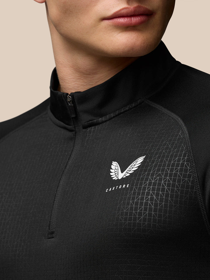 Close-up of black Adapt Print Quarter Zip Top showing stand collar and allover geometric pattern with Castore branding on the chest