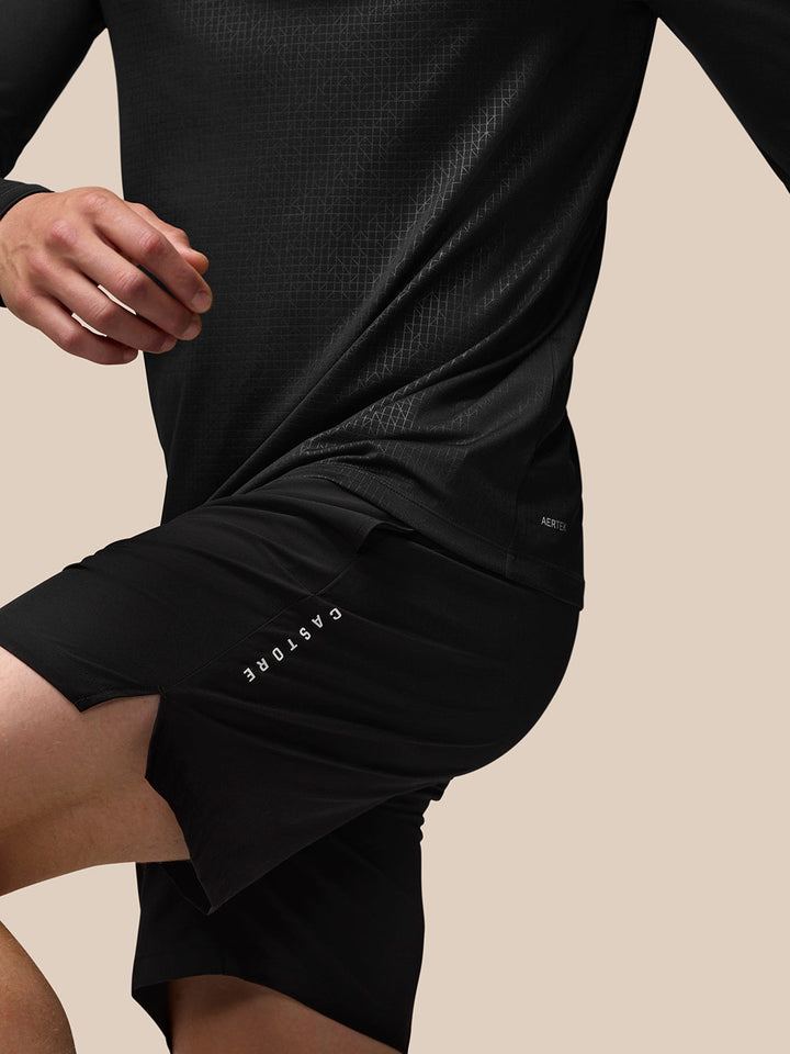 Rear view of model in black athletic outfit with geometric pattern and CASTORE branding along the shorts