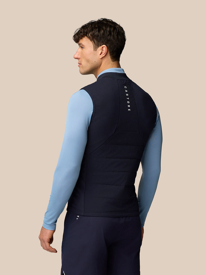 Back view of a man in a navy Apex training gilet with vertical CASTORE branding down the back