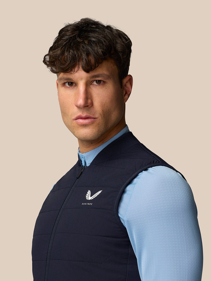 Back and side view of a man in a navy Apex training gilet showing CASTORE branding on upper back and left chest