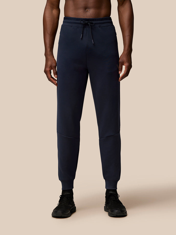 Front view of navy Flex Lifestyle Joggers showing drawstring waist, ribbed cuffs, and Castore branding at left thigh.