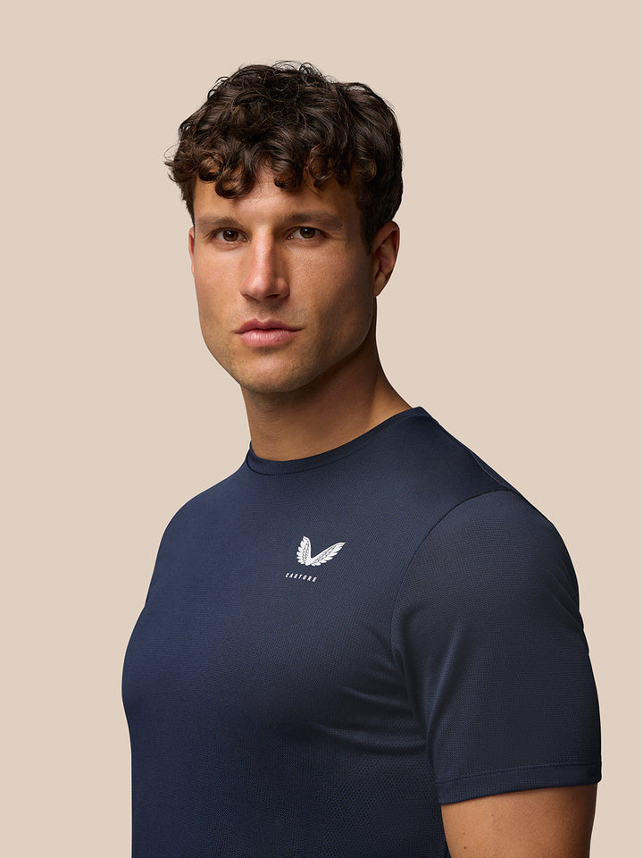 Front three-quarter view of a man in navy Apex Training T Shirt with Castore logo on the chest.