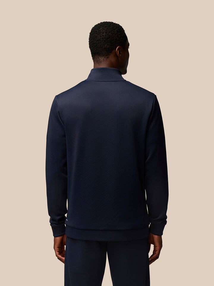 Back view of a man wearing a navy Flex Quarter Zip top with a high collar