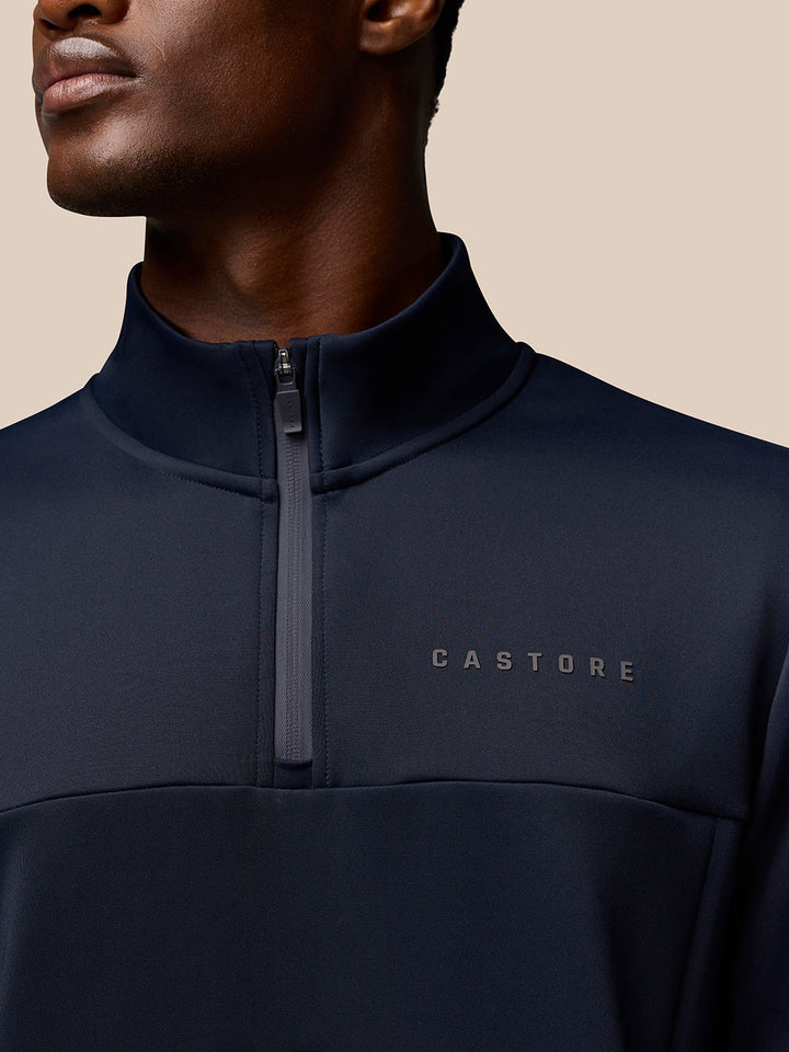 Close up of navy Castore Flex Quarter Zip highlighting the front zipper and left chest Castore logo
