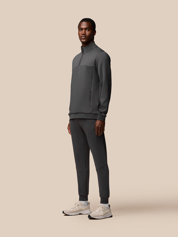 Full-body view of a model in Charcoal Flex Sweatshirt with zip pockets paired with matching joggers and light sneakers.