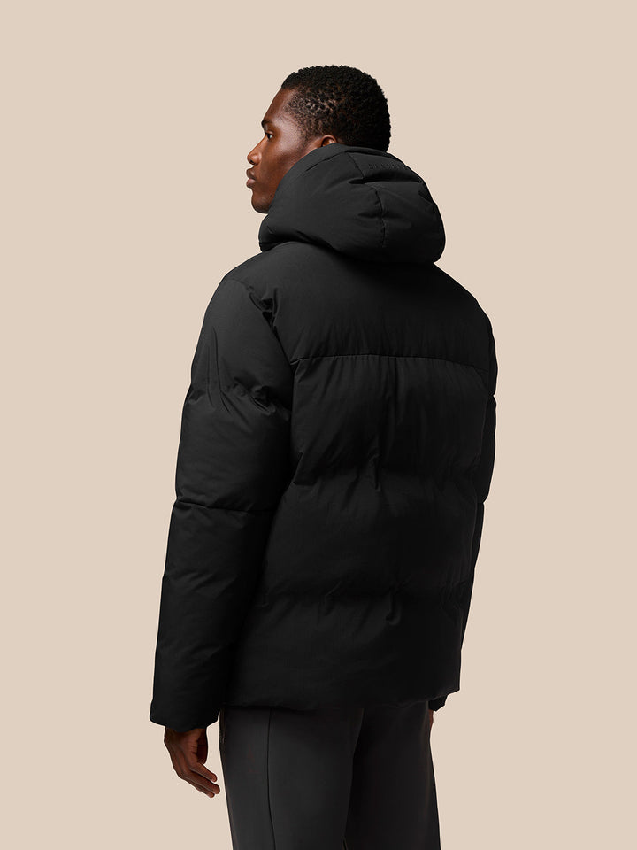 Rear view of a man wearing a black ProTek puffer jacket with hood