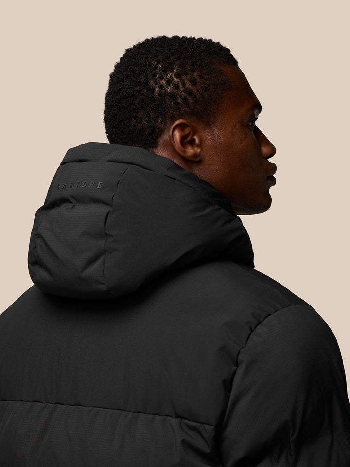Back view of black puffer jacket with hood and Castore branding on the hood