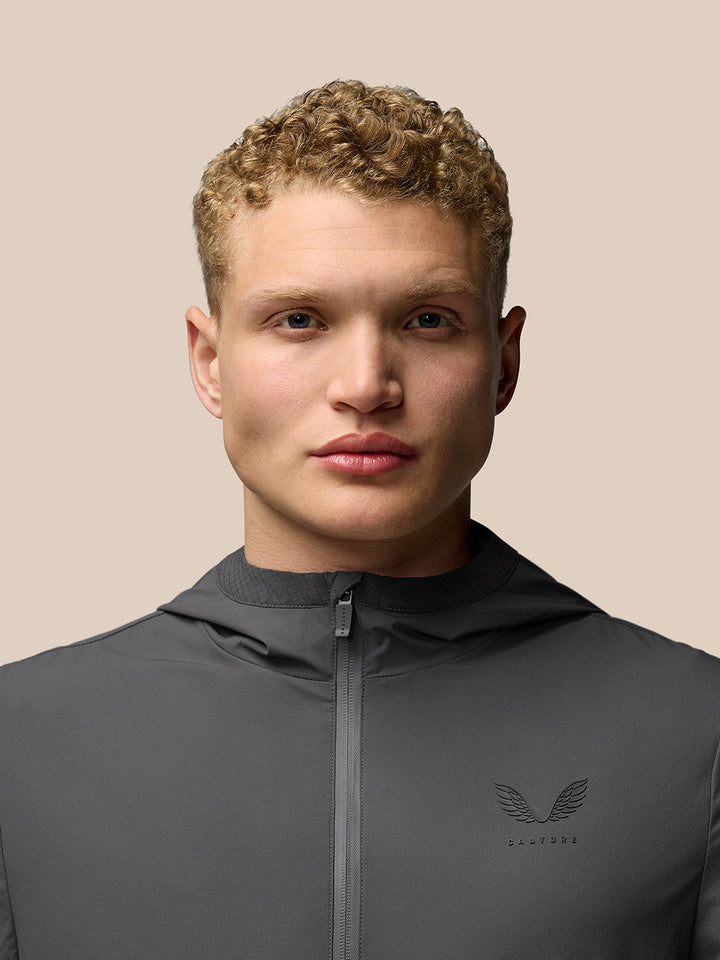 Close up of a model wearing charcoal Lightweight Flex Jacket with a full front zip and left chest logo