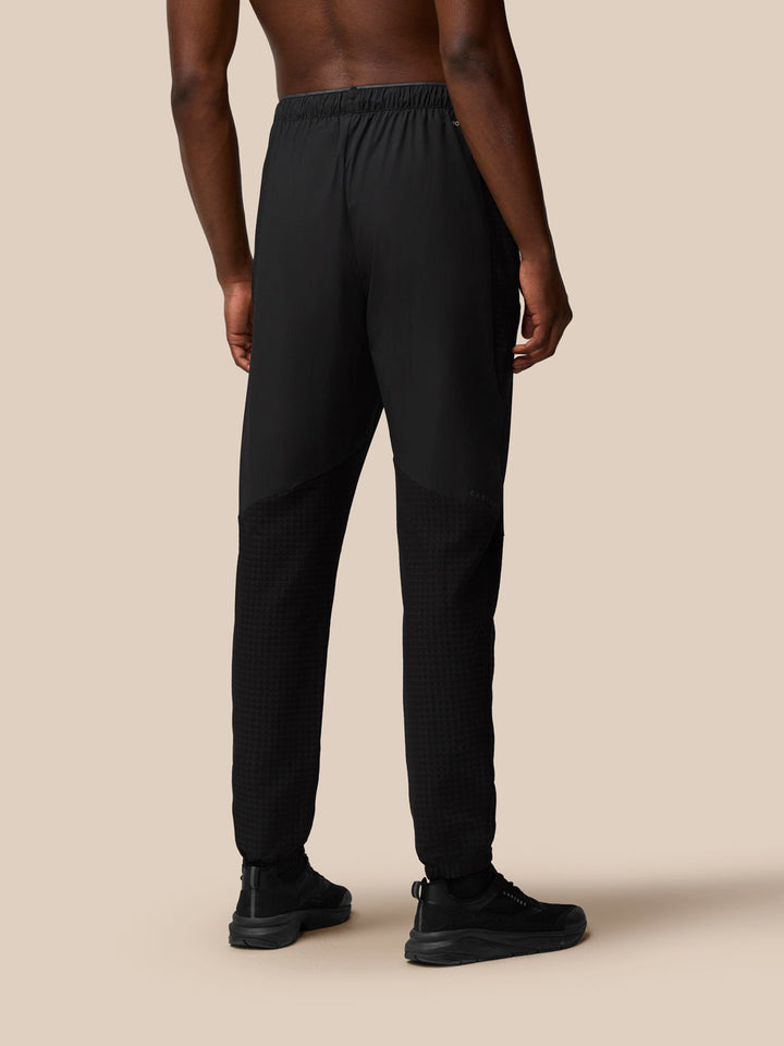 Back view of a man in black Flex Winterised Woven Joggers with textured lower leg panels.