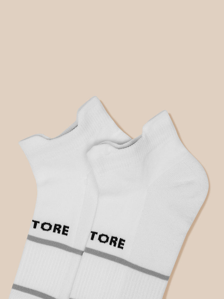 Pair of white ankle length Active Training Socks with Castore branding and gray stripe bands on a beige background