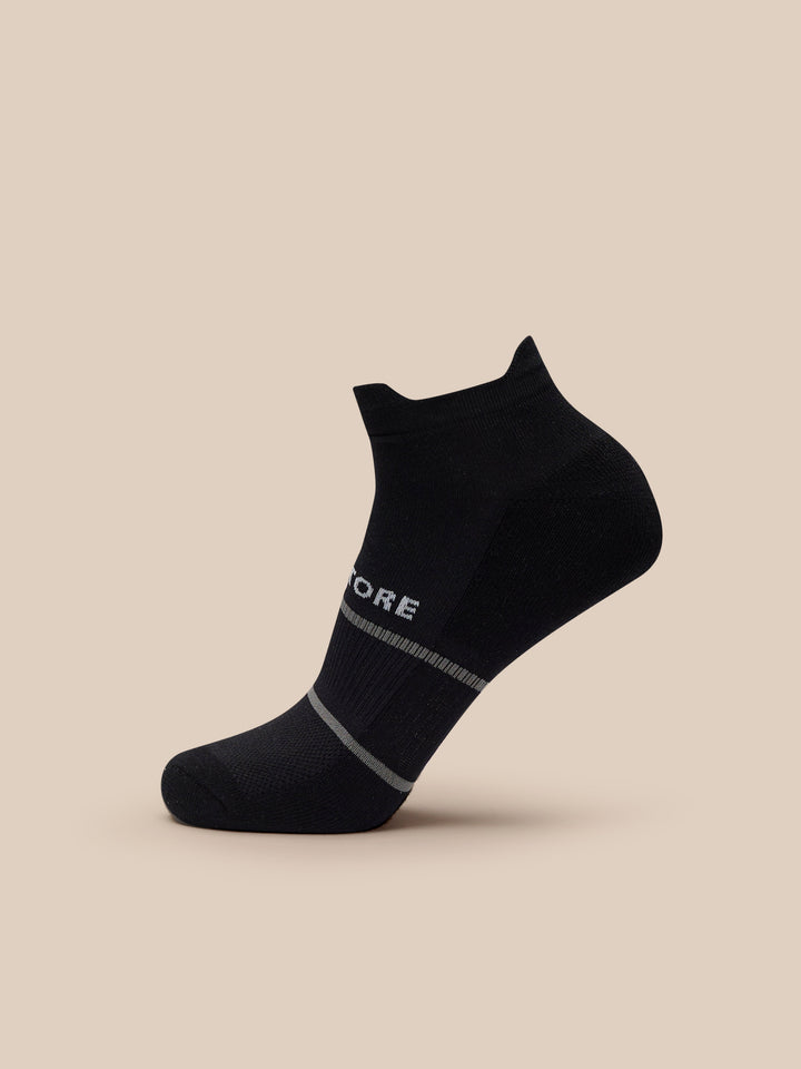 Close up of a black athletic sock with white CASTORE branding and gray stripes at the cuff
