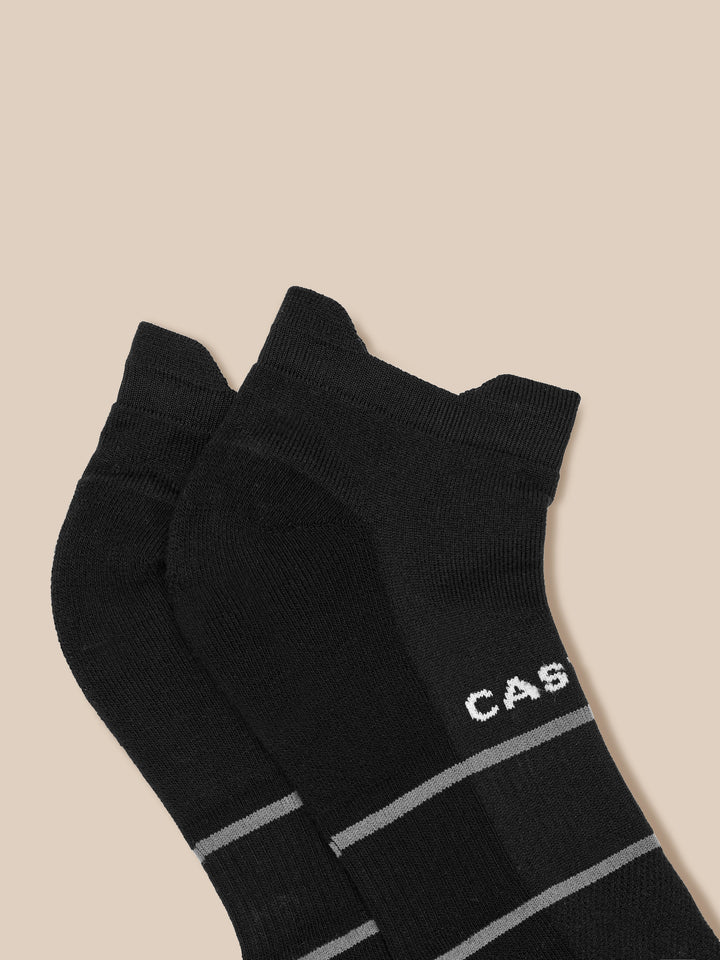 Close-up of black knit Active Training Socks with gray stripe cuffs against a beige background