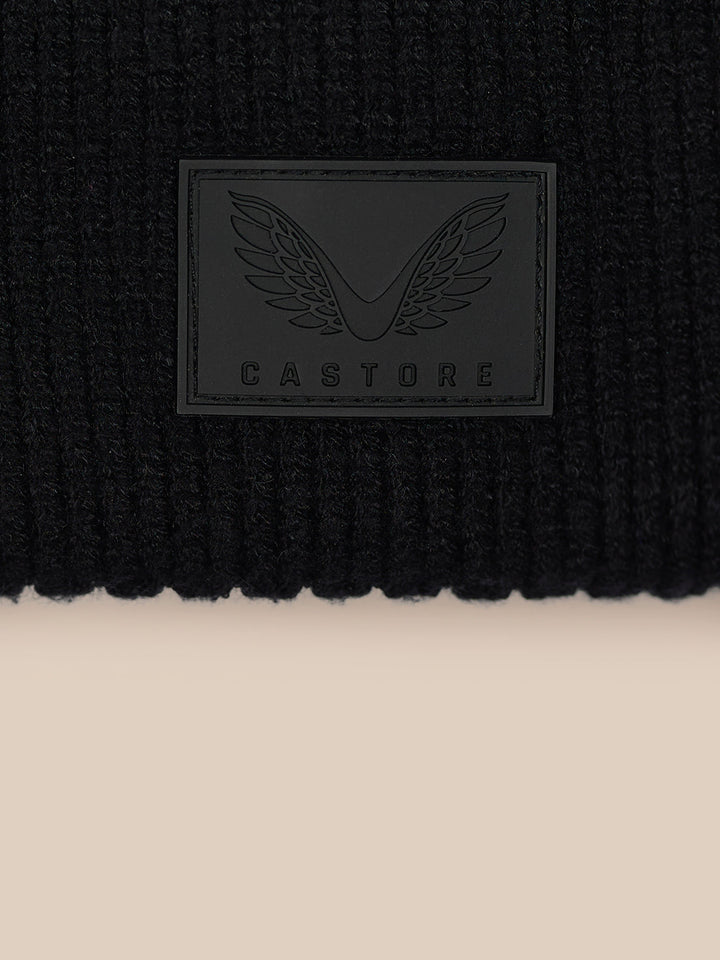 Close-up of the Castore logo patch on the black knit beanie cuff