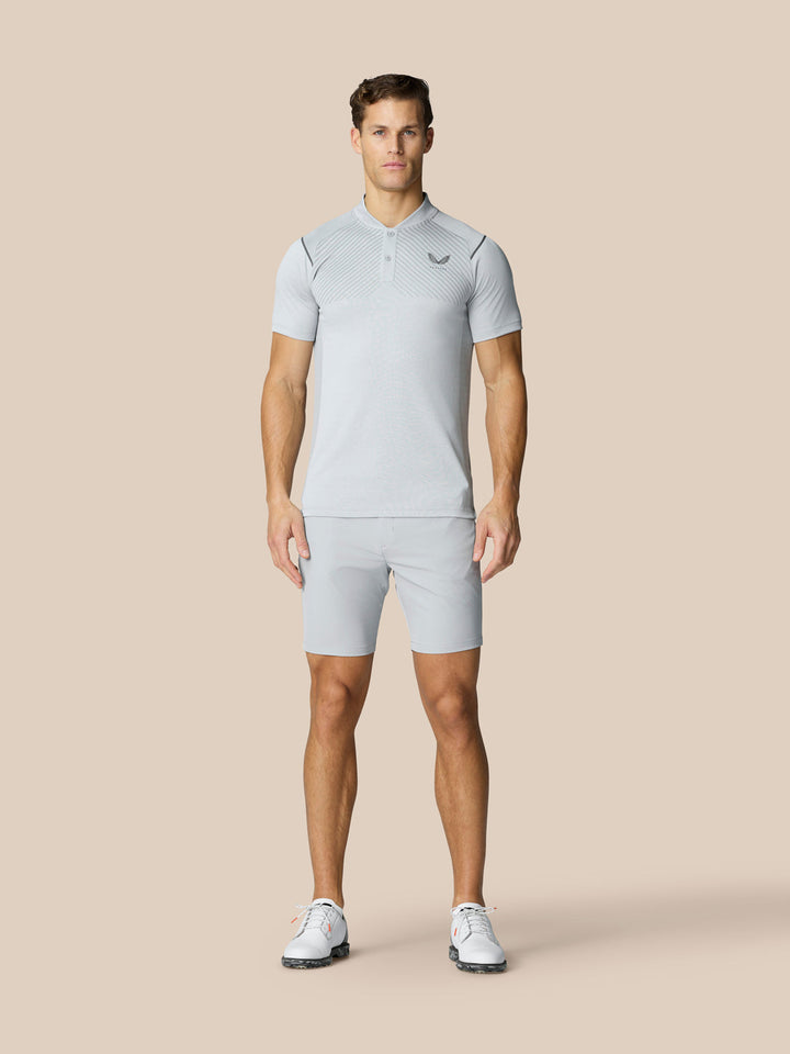 Male model wearing light grey golf shorts with a matching polo on a neutral backdrop.