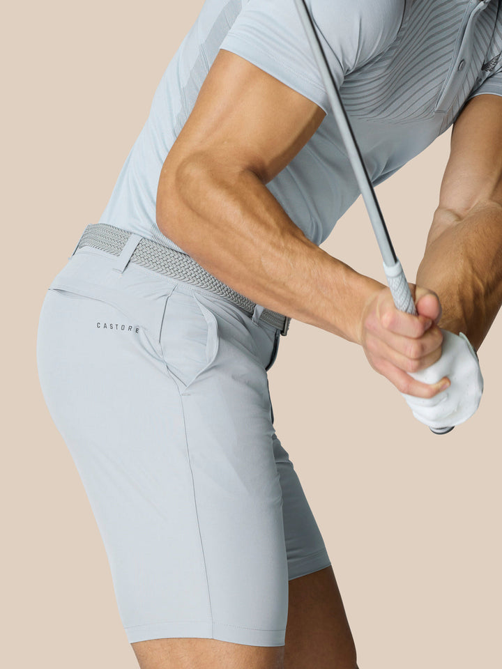 Profile view of a man wearing light grey golf shorts with a braided belt; Castore branding on the thigh and rear.