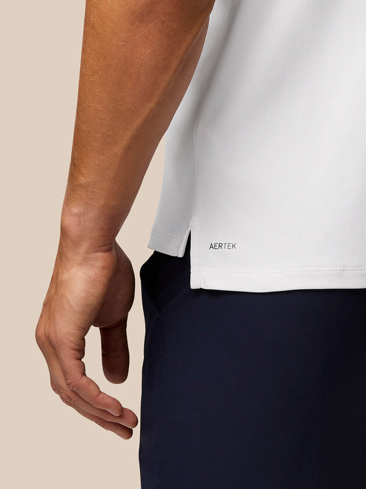 Close up of white Golf Club Essential Polo hem with AERTEK branding on lower back and a side slit