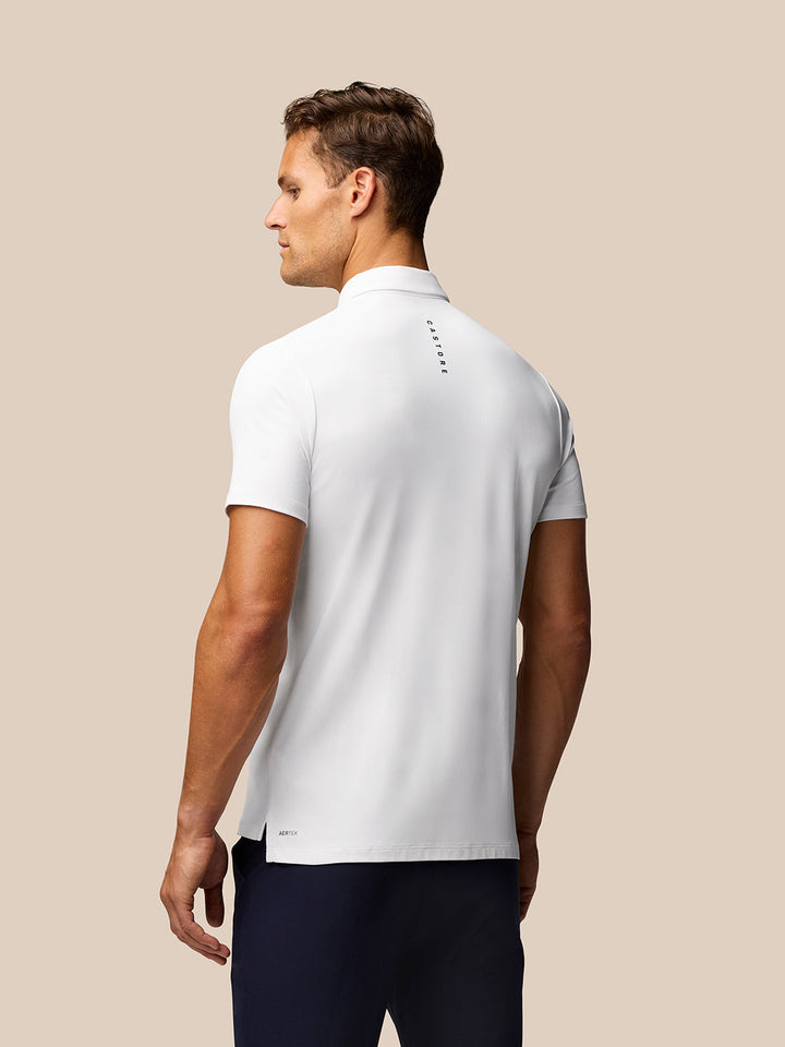 Back view of a man in a white Golf Club Essential Polo with Castore branding along the upper back and Aertek branding at the lower back