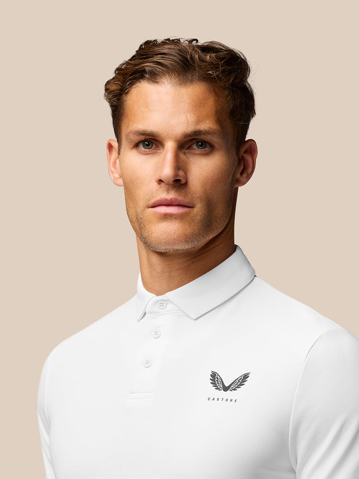 Male model wearing white Golf Club Essential Polo with Castore logo on left chest against beige backdrop