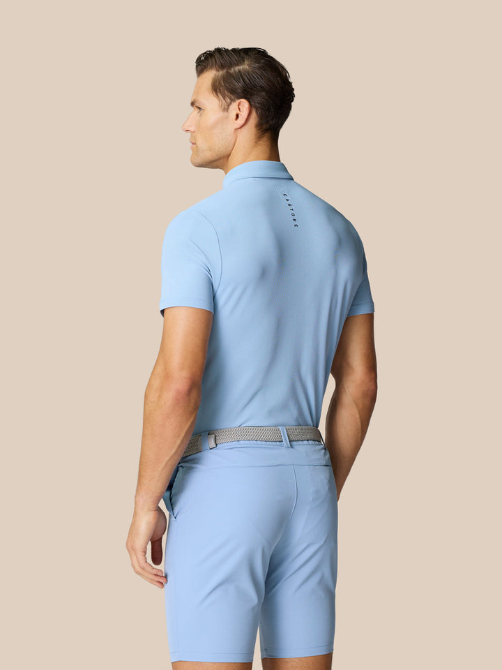 Back view of a man wearing a sky blue Golf Club Essential Polo with Castore branding on the upper back.