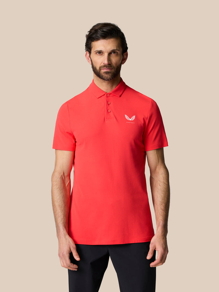 Male model wearing Golf Club Essential Polo in poppy red with Castore logo on the left chest