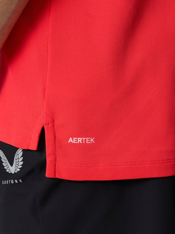 Close-up of the red polo hem with AERTEK branding and textured fabric.