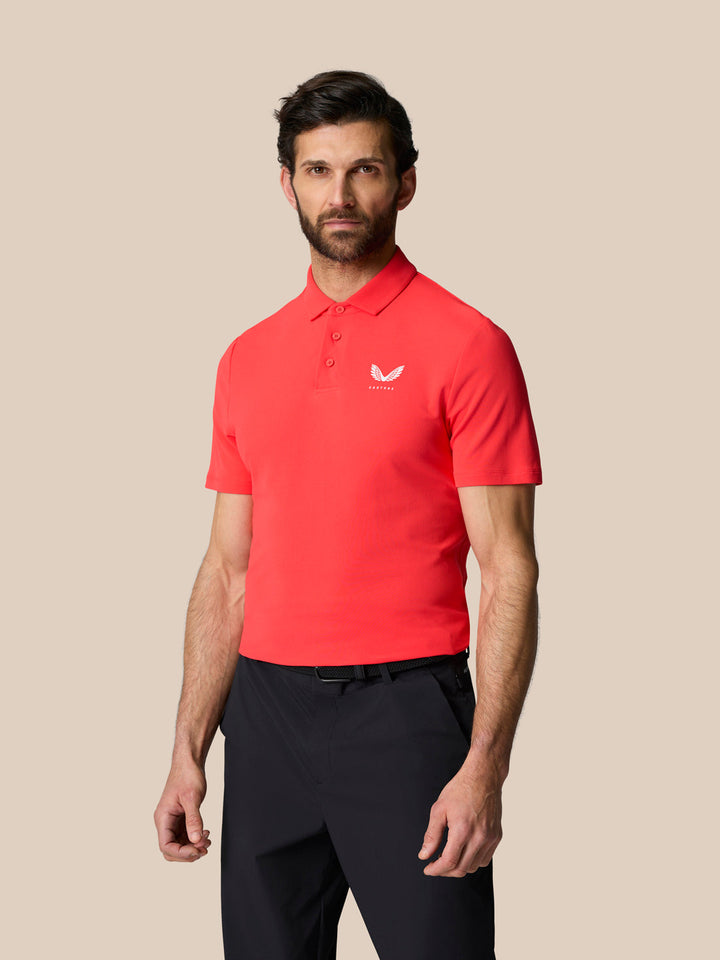 Male model wearing bright red Golf Club Essential Polo with a white Castore logo on the left chest.