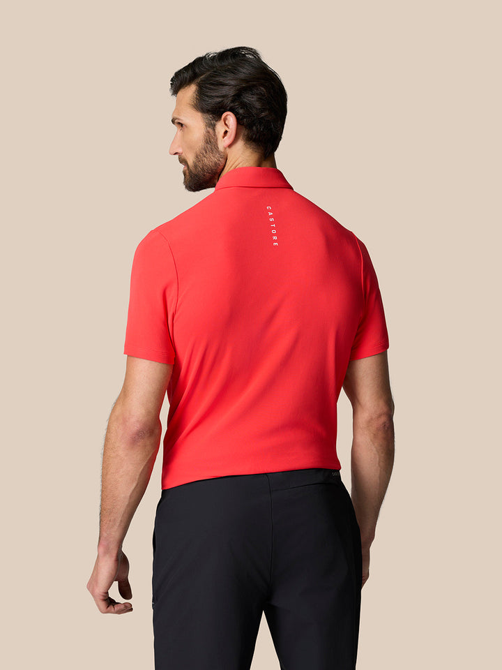 Back view of a man in a bright red Golf Club Essential Polo showing Castore branding along the upper back.
