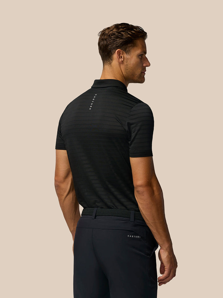 Back view of a man in a black Pinnacle Pique Stripe Polo with subtle stripes and Castore branding on the upper back.