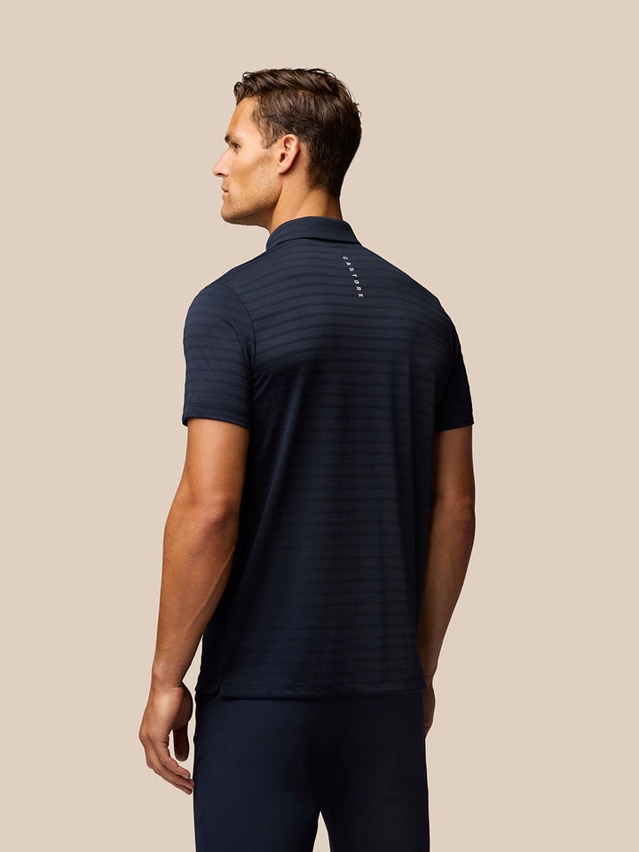 Back view of navy Pinnacle Stripe Polo with stripe texture and Castore branding along upper back.
