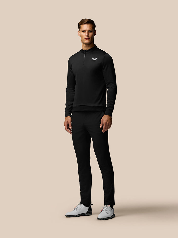 Male model wearing black Golf Club Classic 1/4 Zip Top with stand collar and logos on chest and upper back.