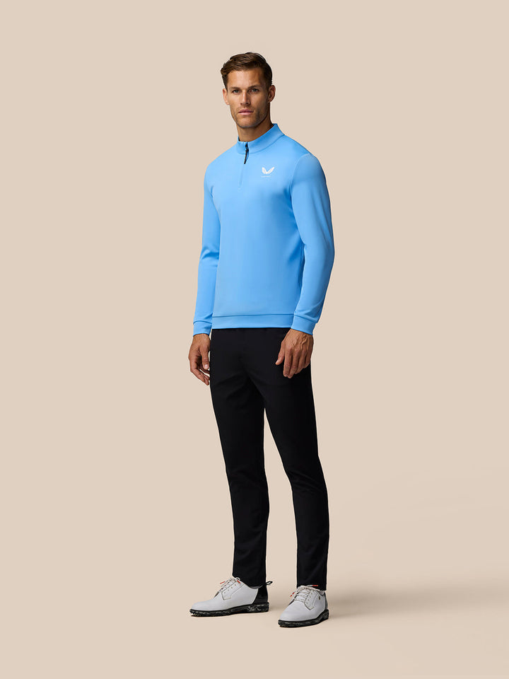 Full-length shot of a man in a light blue Golf Club Classic 1/4 Zip Top with Castore logo on the left chest