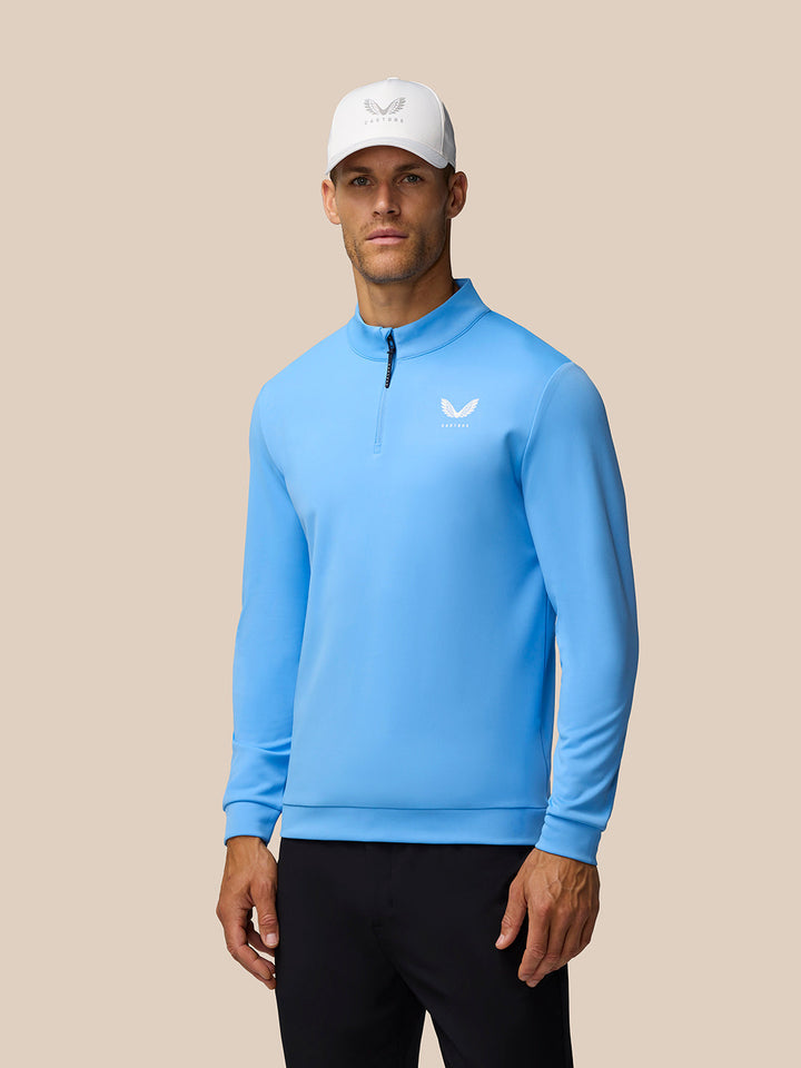 Male model wearing cool blue golf top with left chest logo and white cap.