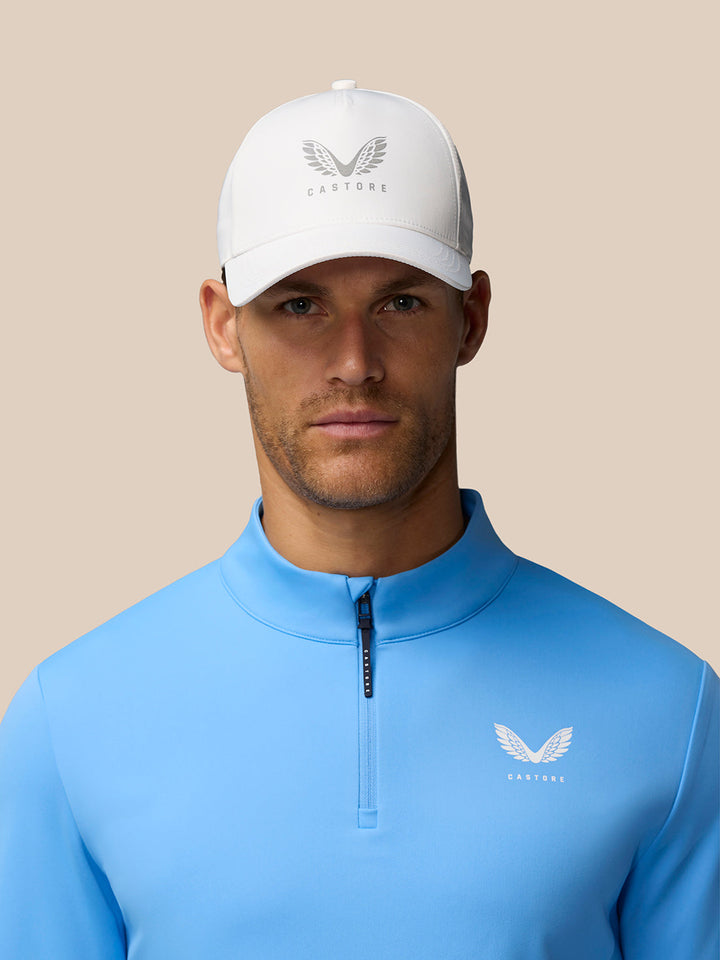 Front view of a man in a light blue Golf Club Classic 1/4 Zip Top with chest logo and white cap
