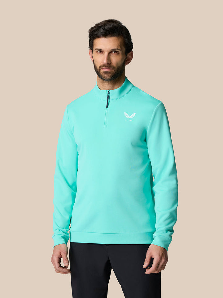 Man wearing light aqua Golf Club Classic Quarter Zip Top with stand collar and Castore logo on left chest