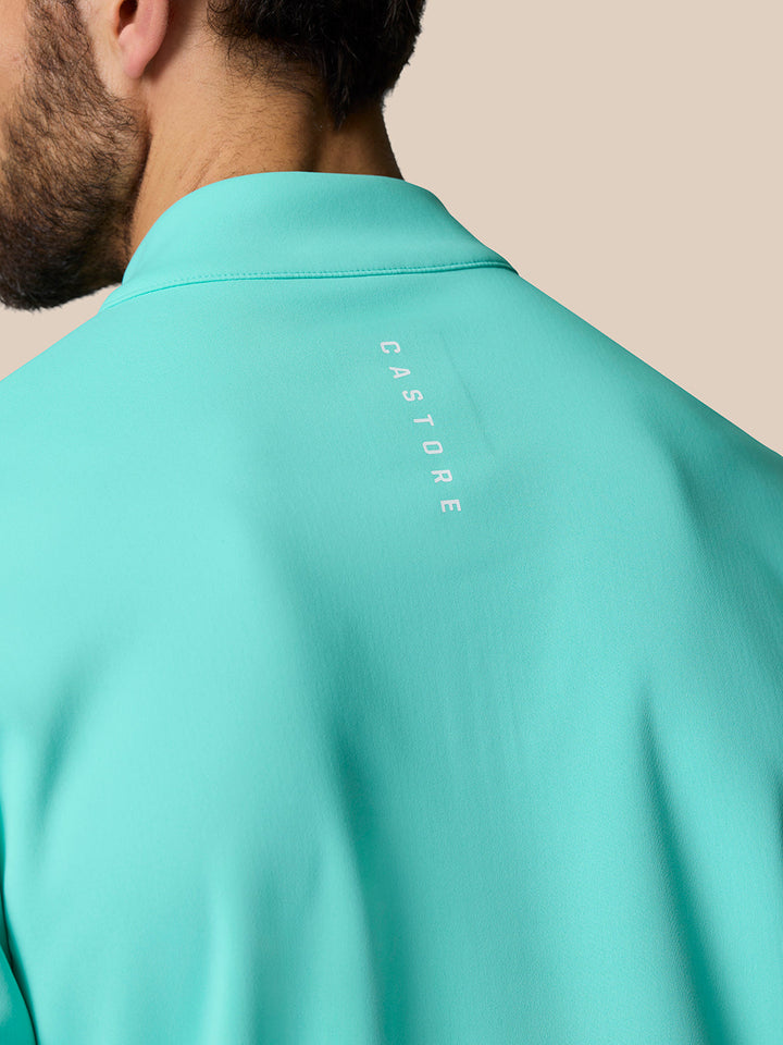 Back view of mint aqua golf top with vertical CASTORE branding along the upper back
