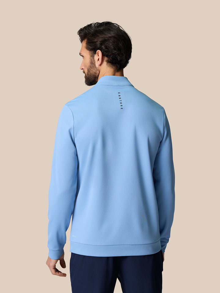 Back view of sky blue long sleeve golf top with Castore branding near the upper back.