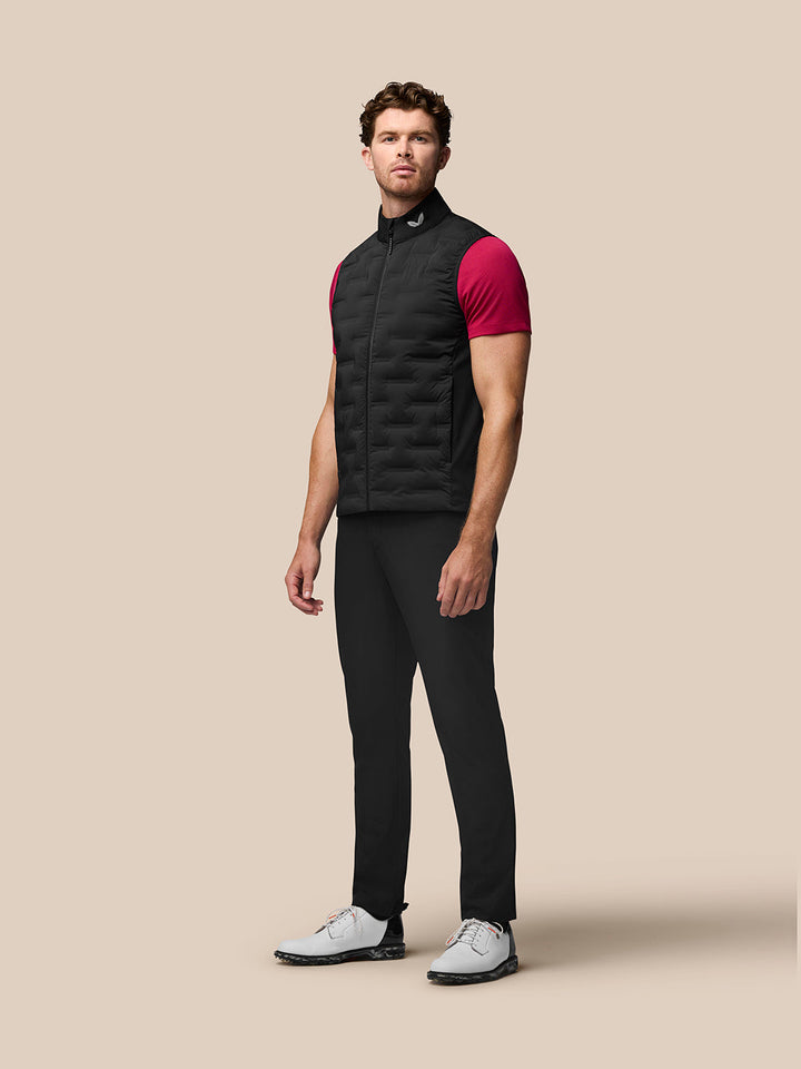 Male model wearing black Pinnacle Gilet with stand collar and front zip over a magenta shirt.